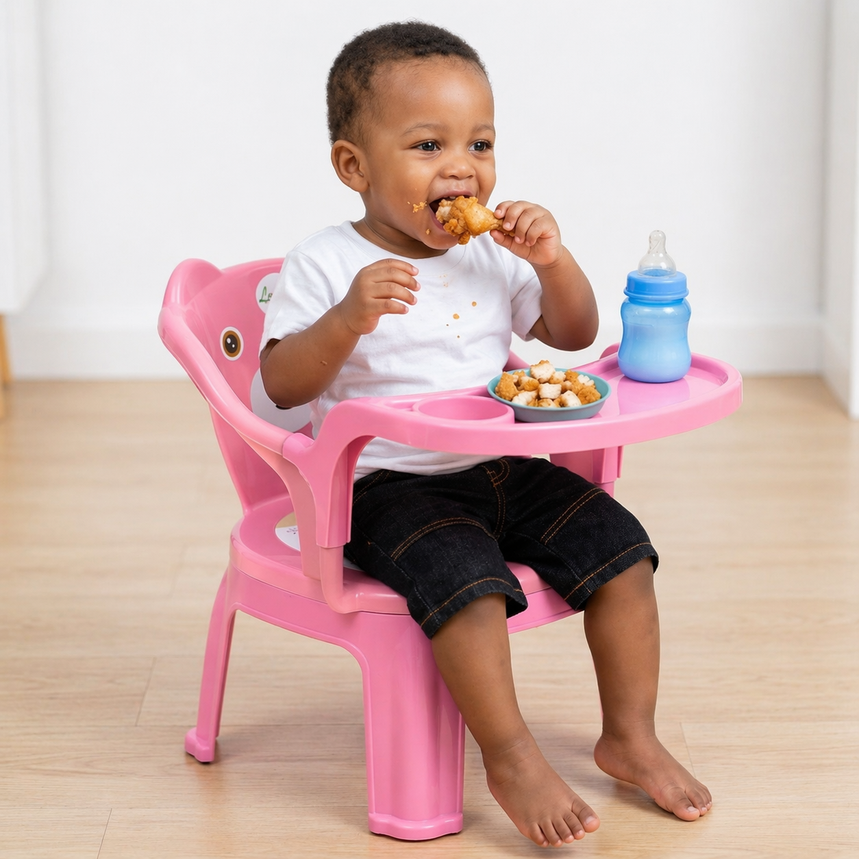 Chaise de repas pour enfant en plastique bicolore bleu et corail avec un large plateau frontal amovible. Le dossier présente un design de petit animal avec des yeux. Produit disponible à Bangui, République Centrafricaine chez 236 Shopping pour 9 990 FCFA.